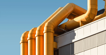 Yellow stack of pipes up the side of an industrial building