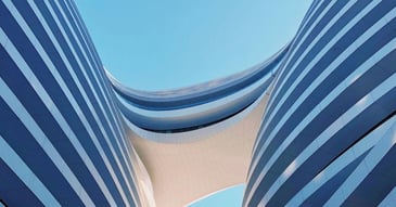 Modern architectural arches stretching upward toward a blue sky, representing the complex systems required for business scaling and the foundational breaking points of revenue operations.